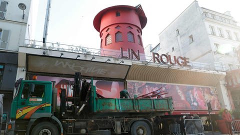 Arbeiter sichern den Bereich vor dem Kabarett, nachdem die Flügel des Windrads des "Moulin Rouge" in der Nacht abgestürzt sind. (Foto: dpa Bildfunk, picture alliance/dpa/AFP | Geoffroy Van Der Hasselt)
