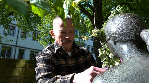 Dithelm Marx tauscht bei einer Statue in einer Tübinger Altstadt die Blumen aus. Das macht er jede Woche. (Foto: SWR)